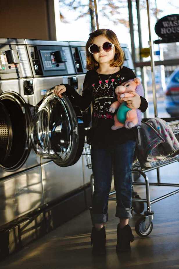 Image of a kid standing near a washing machine